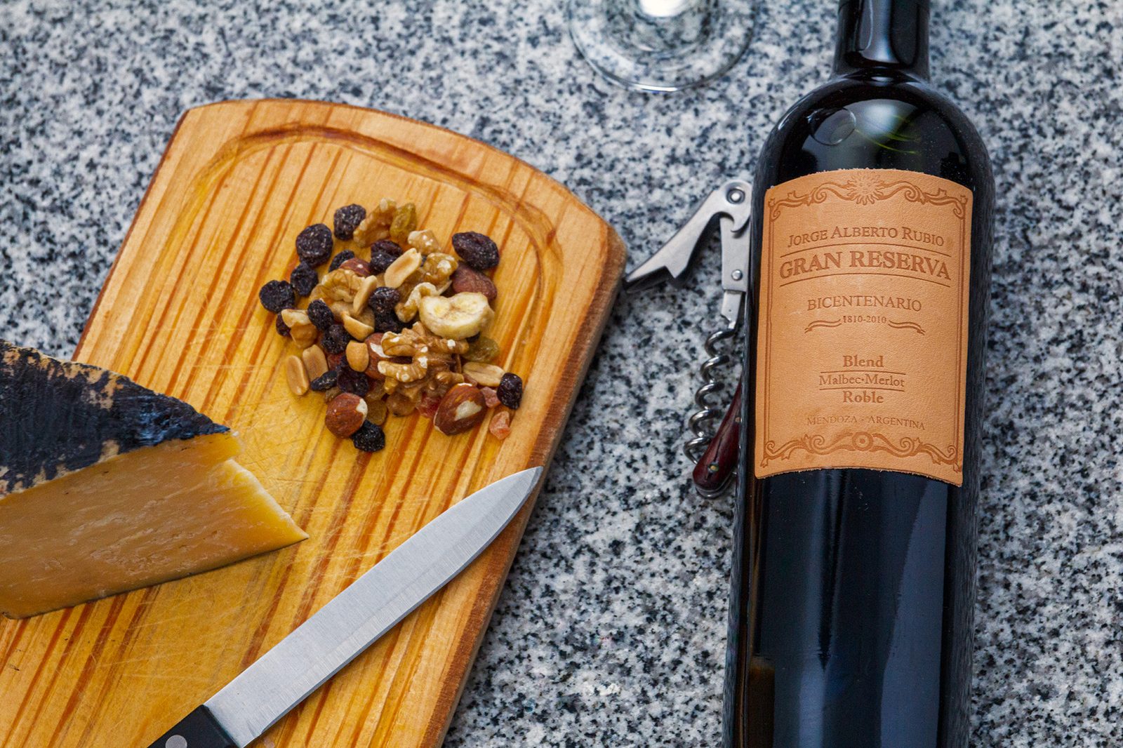 Después: tabla con queso, frutos secos y botella de vino, con luz y color corregidos