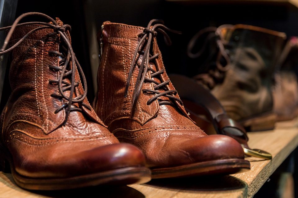 Botas de cuero marrón en un estante de madera, con luz cálida